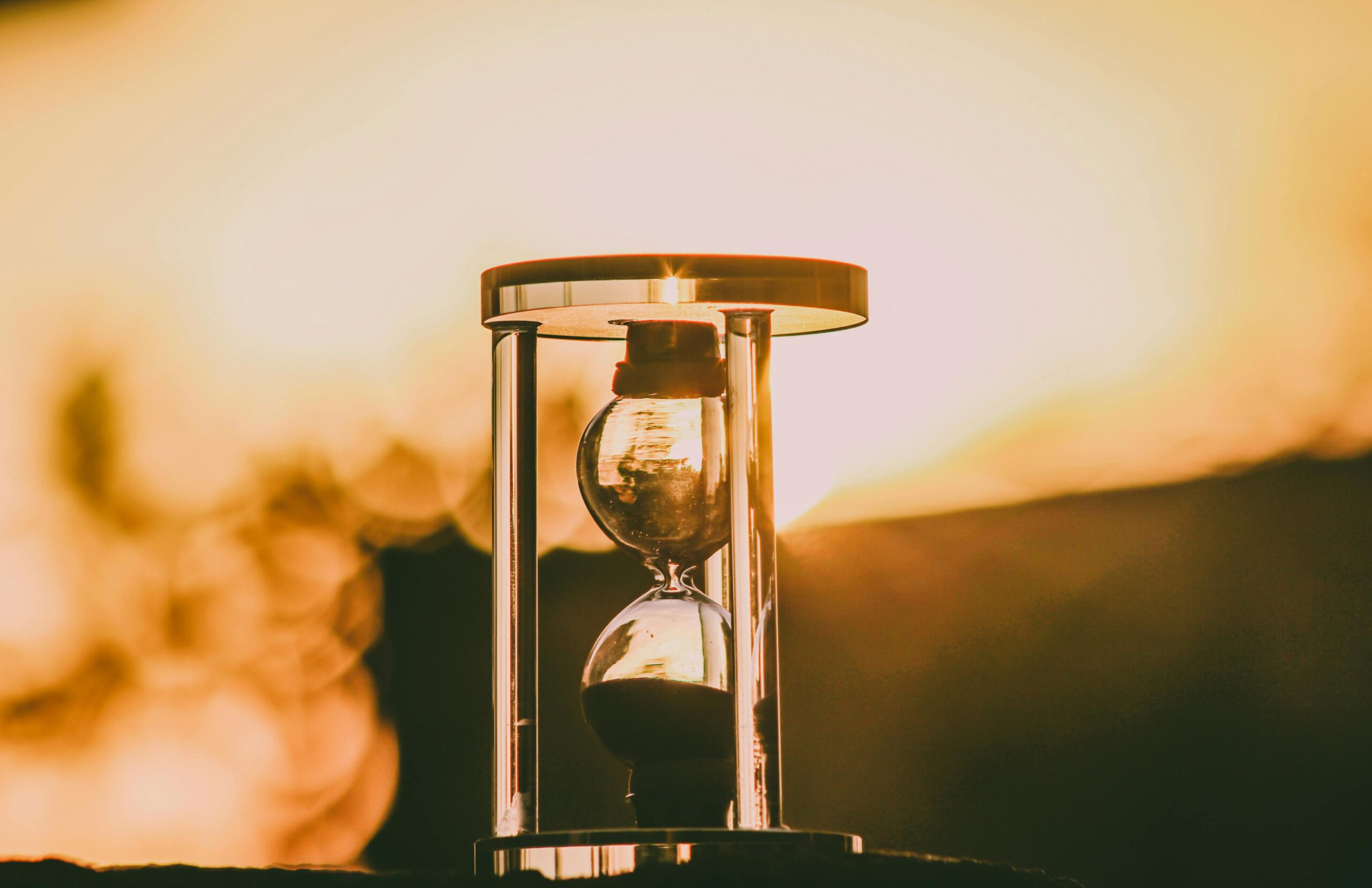 Close-up of an hourglass capturing the essence of time against a sunset backdrop.