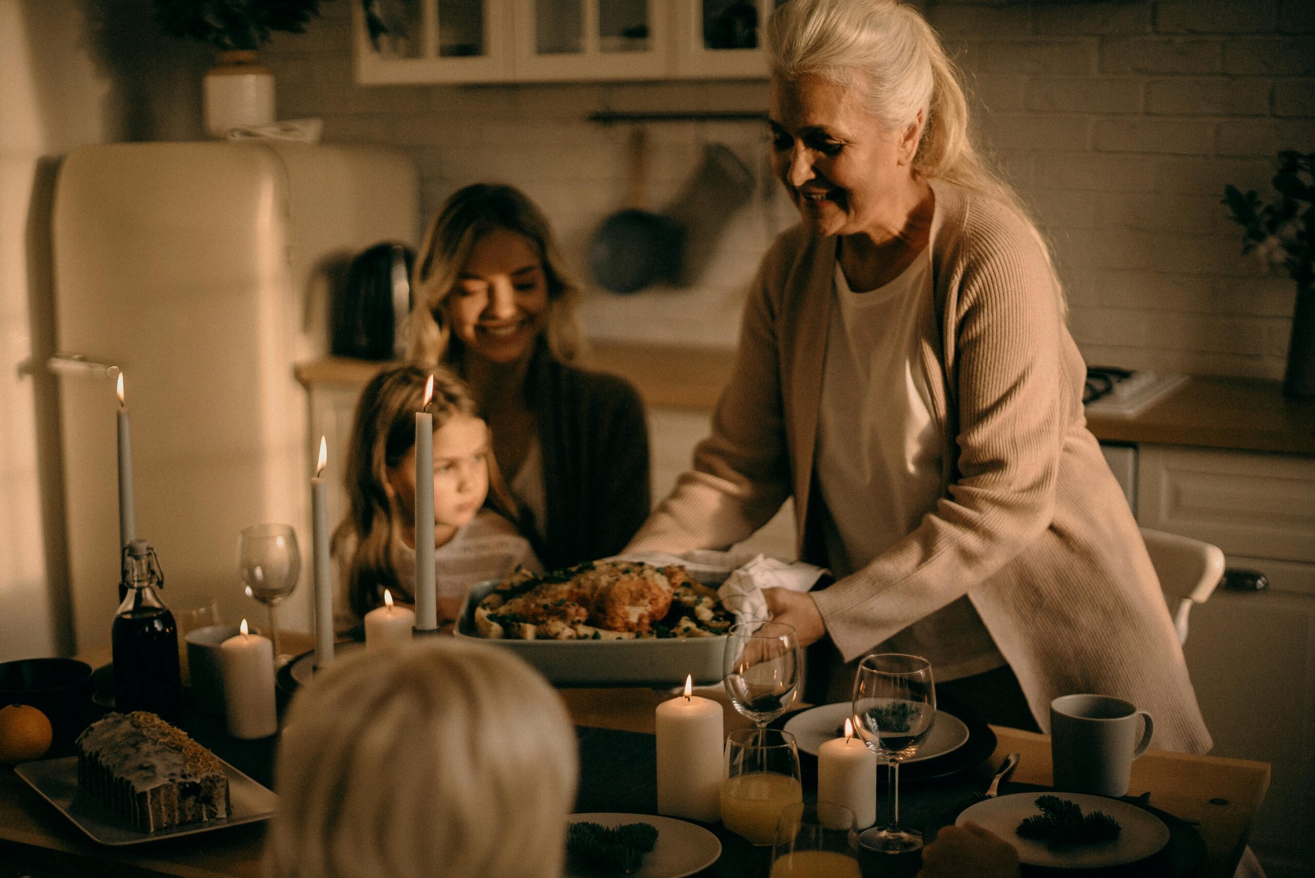 A grandmother serves a festive turkey dinner to family gathered around a warmly lit table.