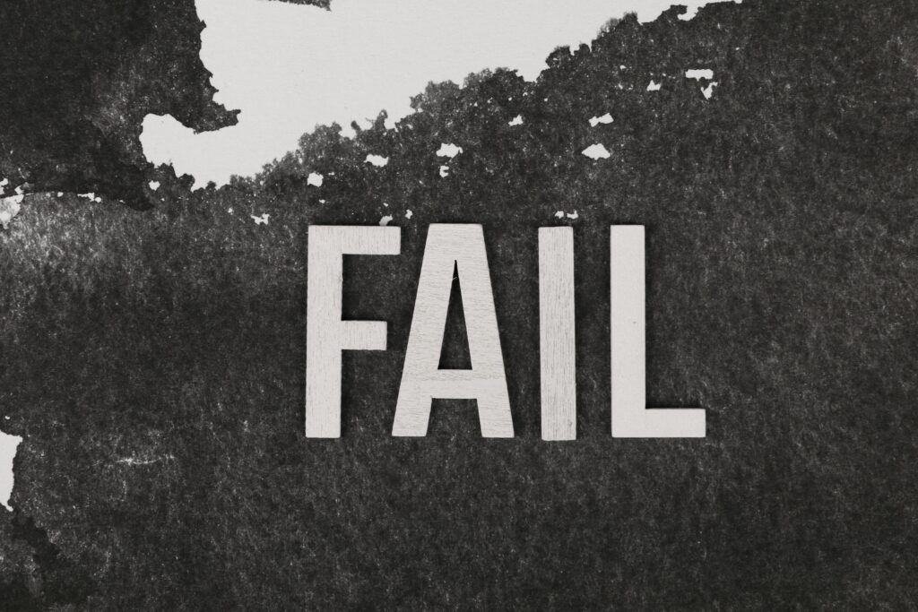 Grayscale image of the word 'FAIL' on a textured, monochrome background.